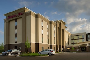 A Hampton Inn hotel with a modern facade, multiple entry points, and a parking lot with cars.