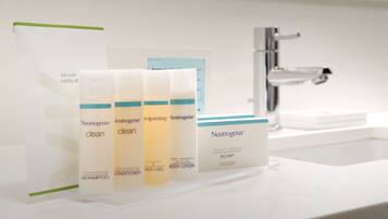 Une salle de bain avec un lavabo blanc et un présentoir où sont exposés des produits Neutrogena.