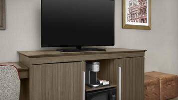 Una cocina moderna con una televisión de pantalla plana montada sobre un mueble de madera, una cafetera y un microondas.