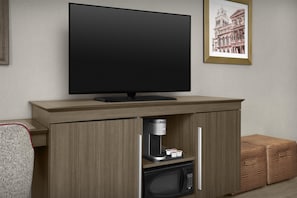 Una cocina moderna con una televisión de pantalla plana montada sobre un mueble de madera, una cafetera y un microondas.