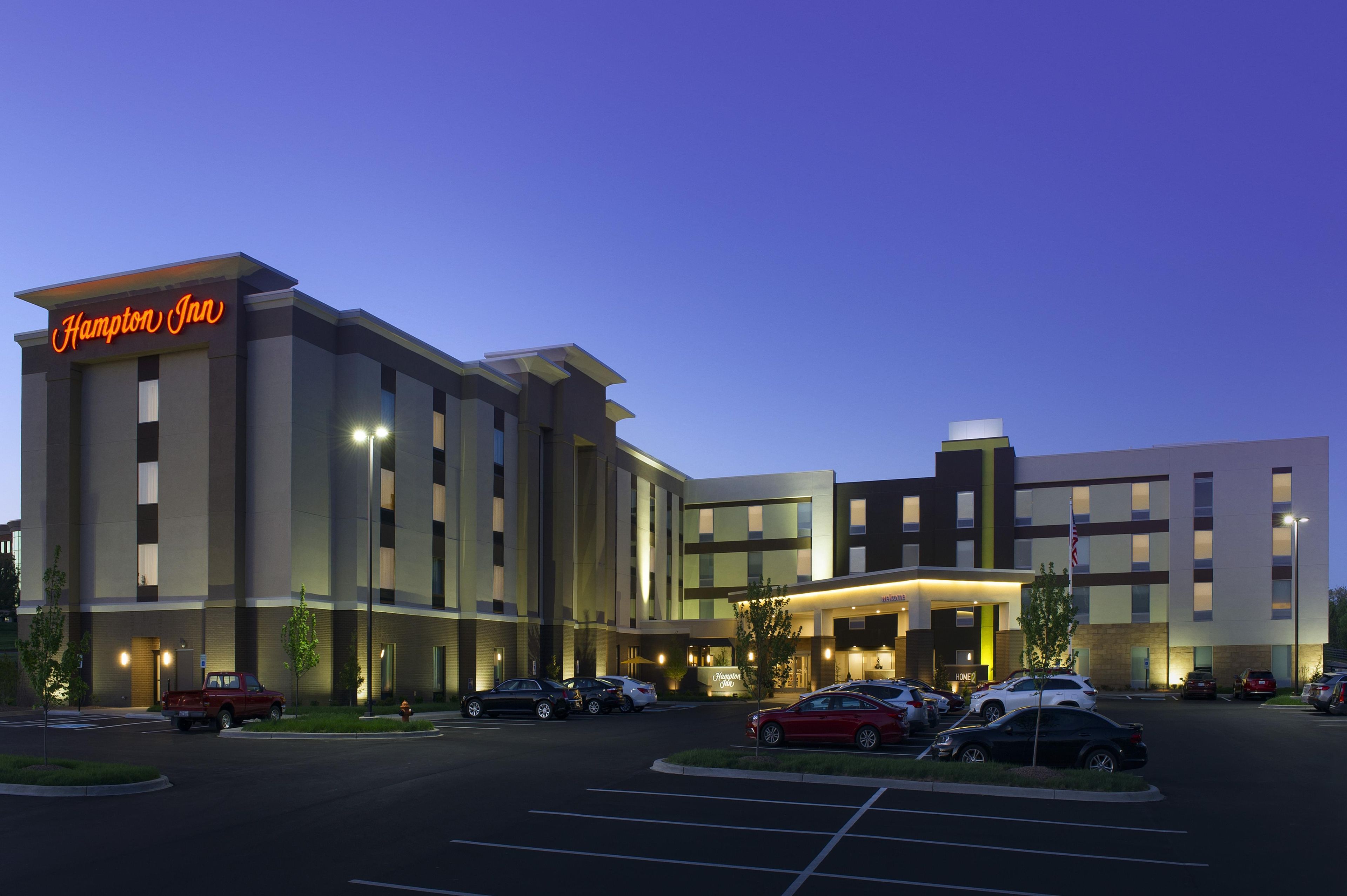 Ein Hampton Inn Hotel mit modernem Design, mehreren Parkplätzen und einem einladenden Eingang.