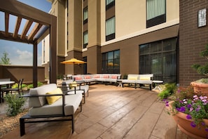 An outdoor patio with a curved sofa, tables, and planters. - Hampton Inn Louisville East/Hurstbourne (Louisville)