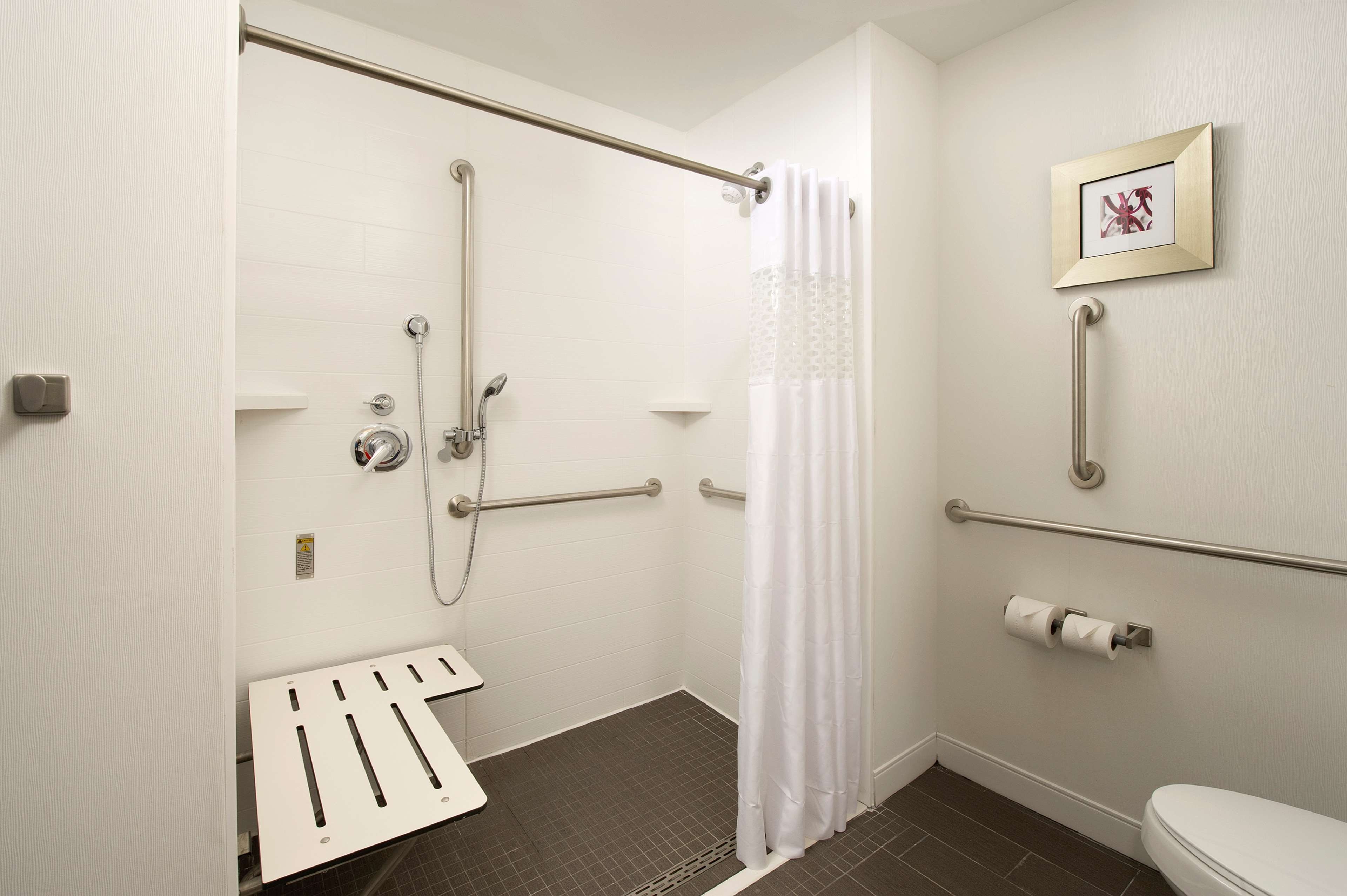 Un baño con ducha, inodoro y barra de apoyo.