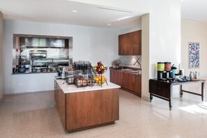 A modern kitchen with a central island, a built-in oven, and a coffee station. - Hilton Garden Inn Miami Dolphin Mall (Miami)