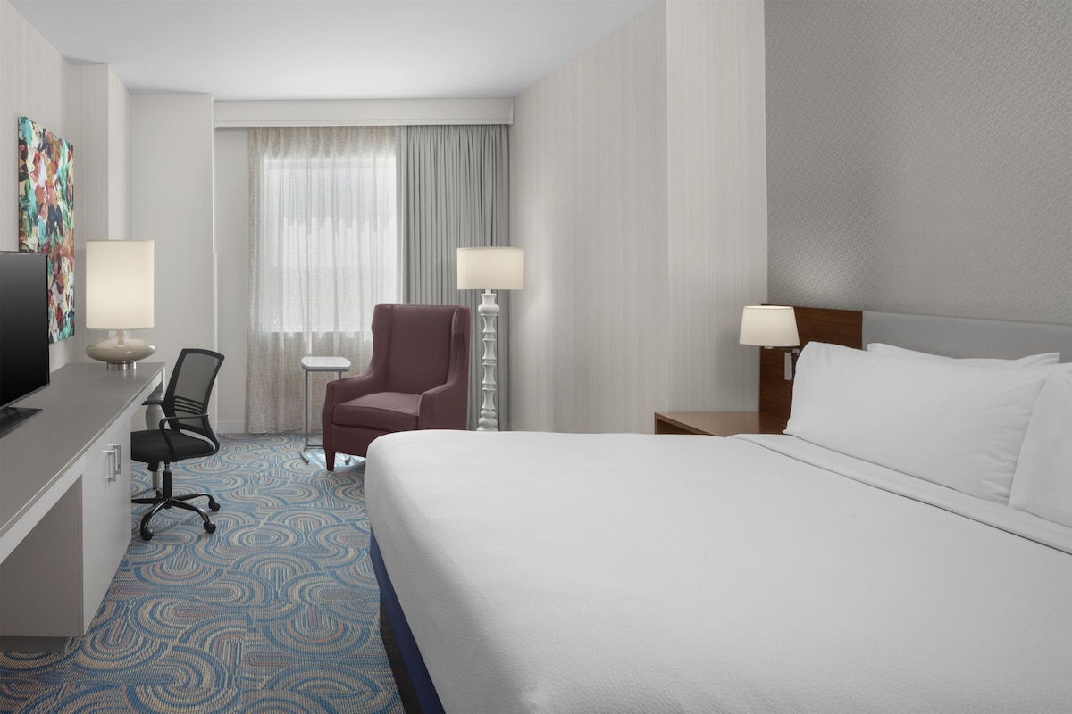Une chambre d’hôtel équipée d’un lit, d’un bureau, d’une chaise, de lampes et d’un téléviseur.