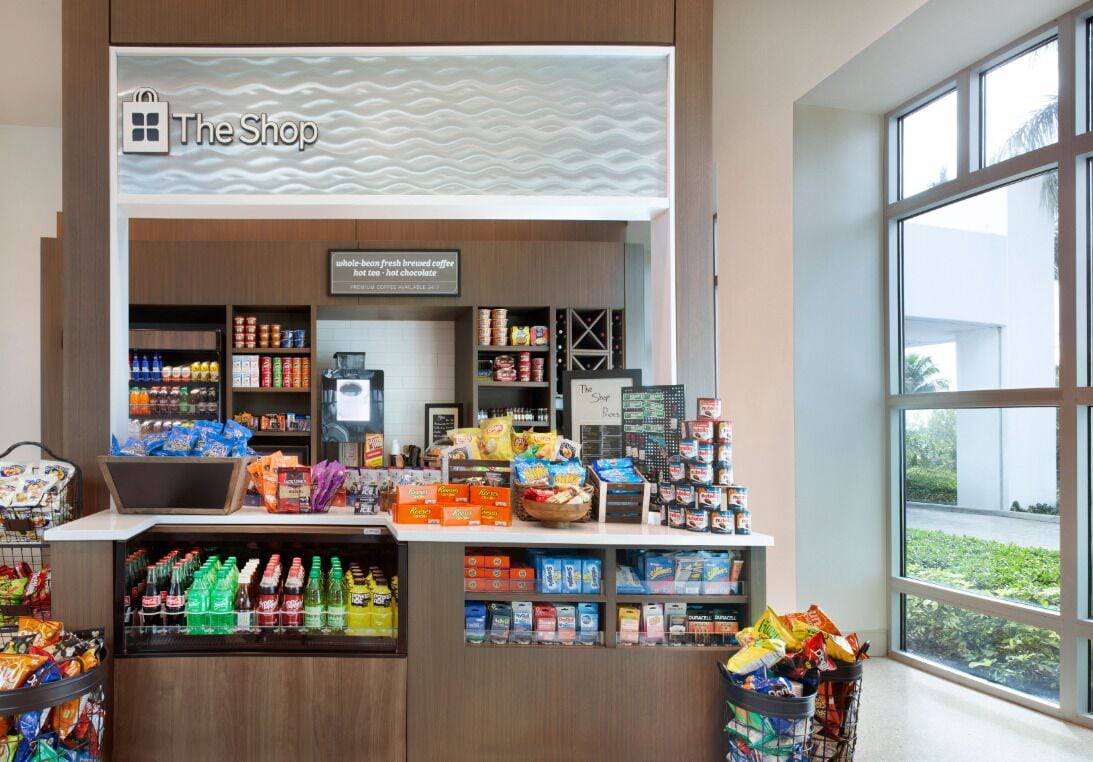A shop counter with a variety of snacks and beverages, a coffee machine, and a sign indicating it offers whole-beam fresh brewed coffee.
