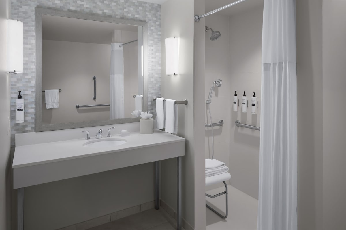 Une salle de bain moderne avec un grand miroir, deux lavabos, une douche et un porte-serviettes.
