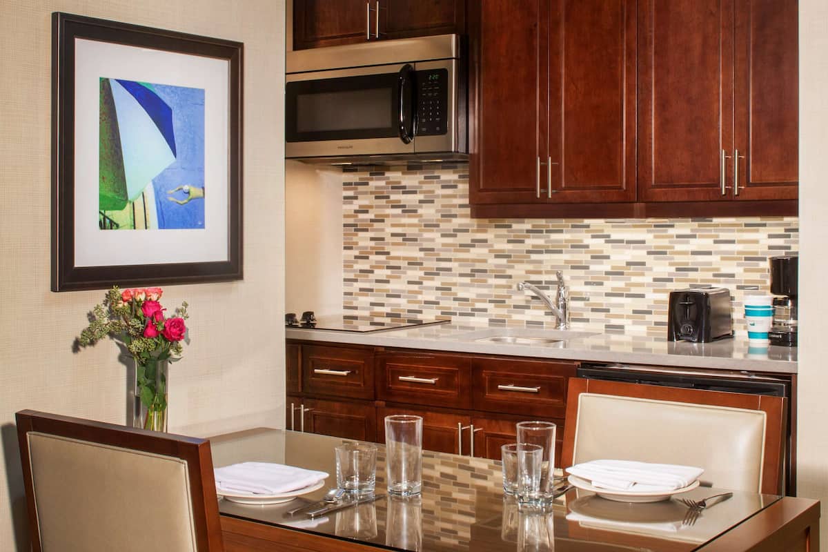 Una cocina moderna con gabinetes de madera, un microondas de acero inoxidable y un salpicadero de azulejos.