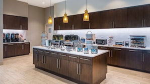 A modern kitchen with dark wooden cabinets, a central island with appliances, and hanging pendant lights.