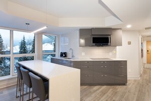 A modern kitchen with a large island, grey cabinets, and a built-in microwave. - Le Chamois by Whistler Premier (Whistler)