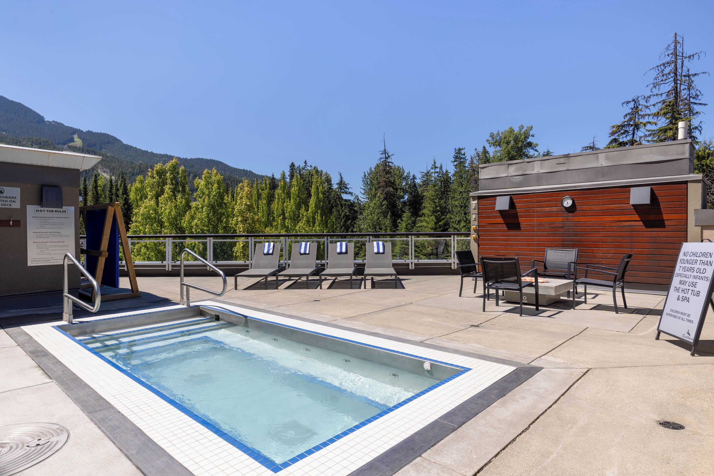 A pool area with a hot tub, lounge chairs, and a sign indicating no children under 7 allowed.