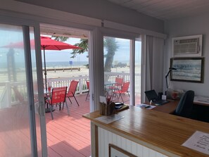 A room with a desk, chairs, and a view of the beach. - Grand View Motel (Hampton)