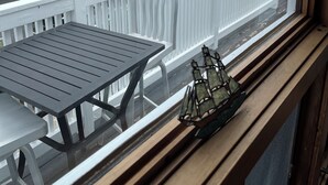 A balcony with a view of a parking lot, a building, and a beach.
