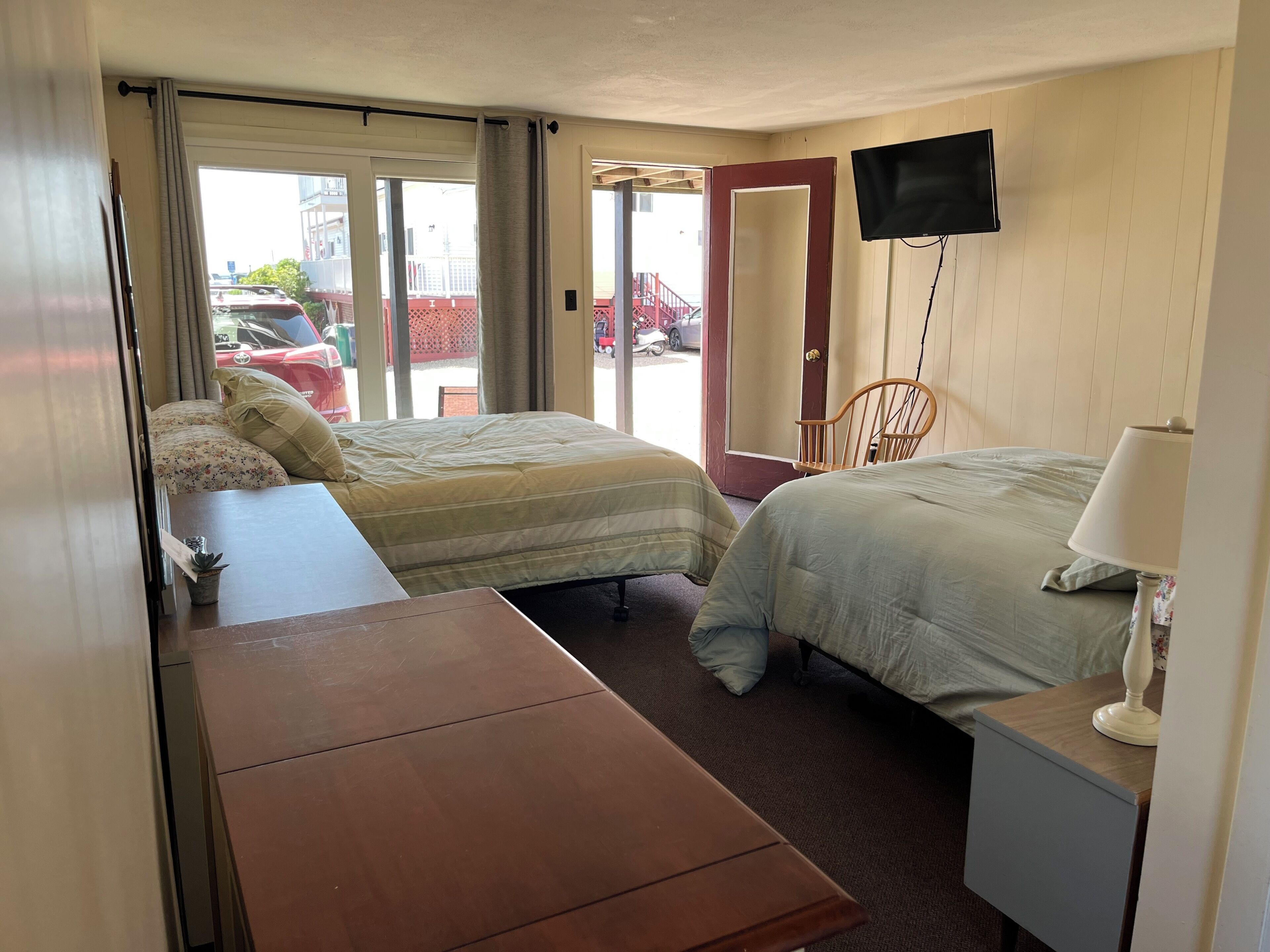 Een hotelkamer met twee bedden, een bureau, een stoel, een televisie en een raam met uitzicht.