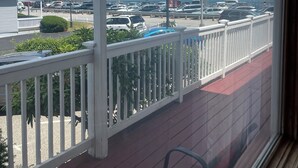 A view from a balcony with a railing, overlooking a parking lot and a body of water.