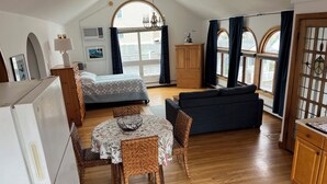 A compact living space with a bed, sofa, dining table, and kitchenette.