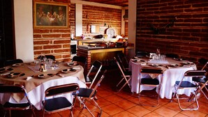 Um restaurante com paredes de tijolo, toalhas de mesa brancas e cadeiras de metal.