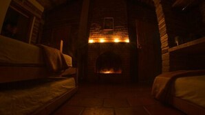 Um quarto acolhedor com lareira, duas camas e soalho de pedra.