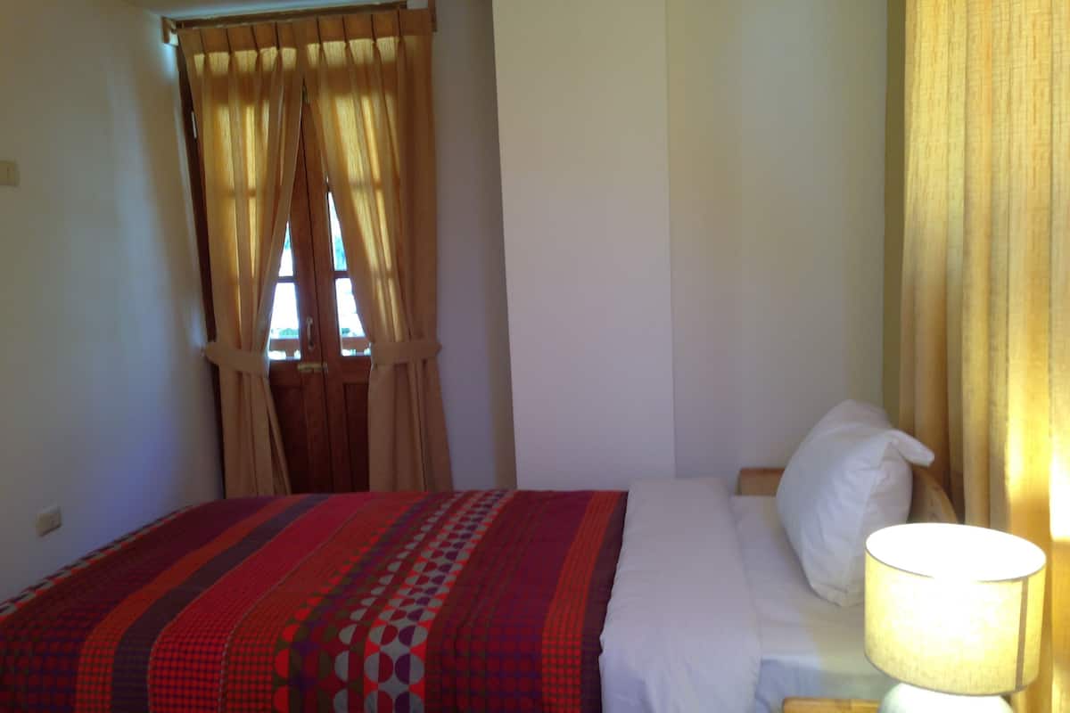 Ein Schlafzimmer mit einem Bett, einer Nachttischlampe und Vorhängen.