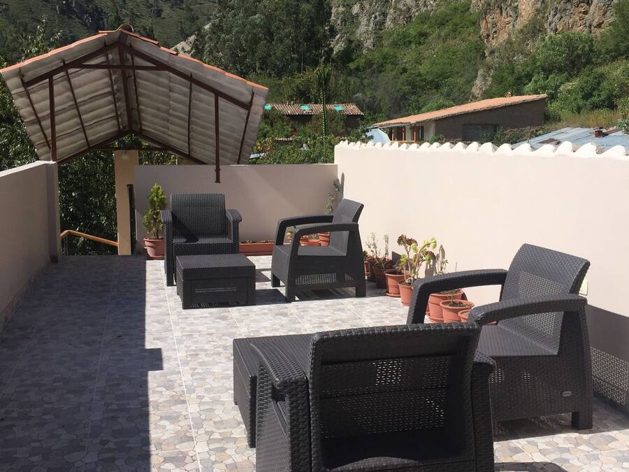 Un patio con mobiliario de mimbre, plantas en macetas y vistas a montañas.