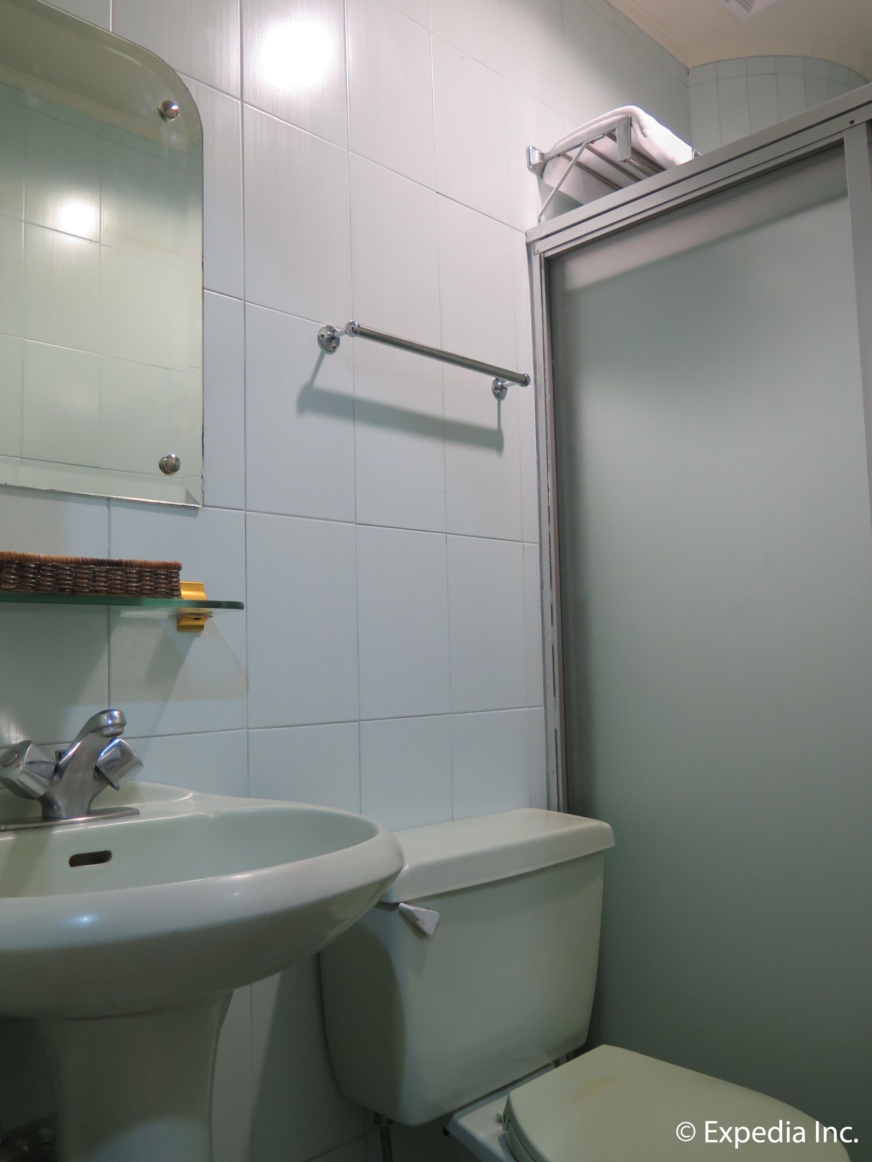 Un baño con un lavabo blanco, un espejo, un perchero para toallas y un inodoro.
