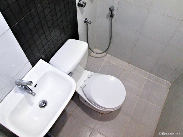 Un baño con inodoro blanco, lavabo y ducha.