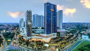 A modern high-rise building with multiple floors, surrounded by a well-lit urban area with roads and greenery. - Hotel Grand Sumatera (Surabaya)