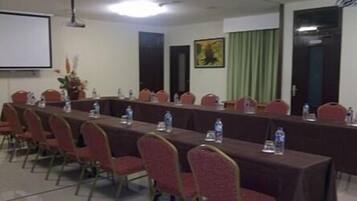 A conference room with a long table, chairs, water bottles, and a projector screen.