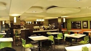 Um restaurante com várias mesas e cadeiras, um balcão com menu e uma parede com quadros emoldurados.
