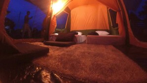 A tent with two beds and a central light source.