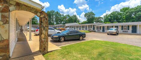 A motel with a stone archway entrance, a parking lot with several cars, and a grassy lawn.
