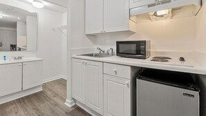 A modern kitchen with white cabinetry, a built-in microwave, and a stainless steel refrigerator.