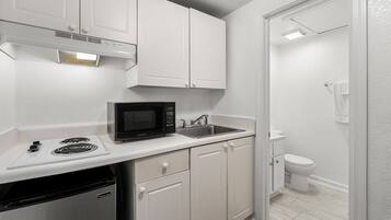 A compact kitchen with white cabinetry, a microwave, a sink, and a dishwasher.