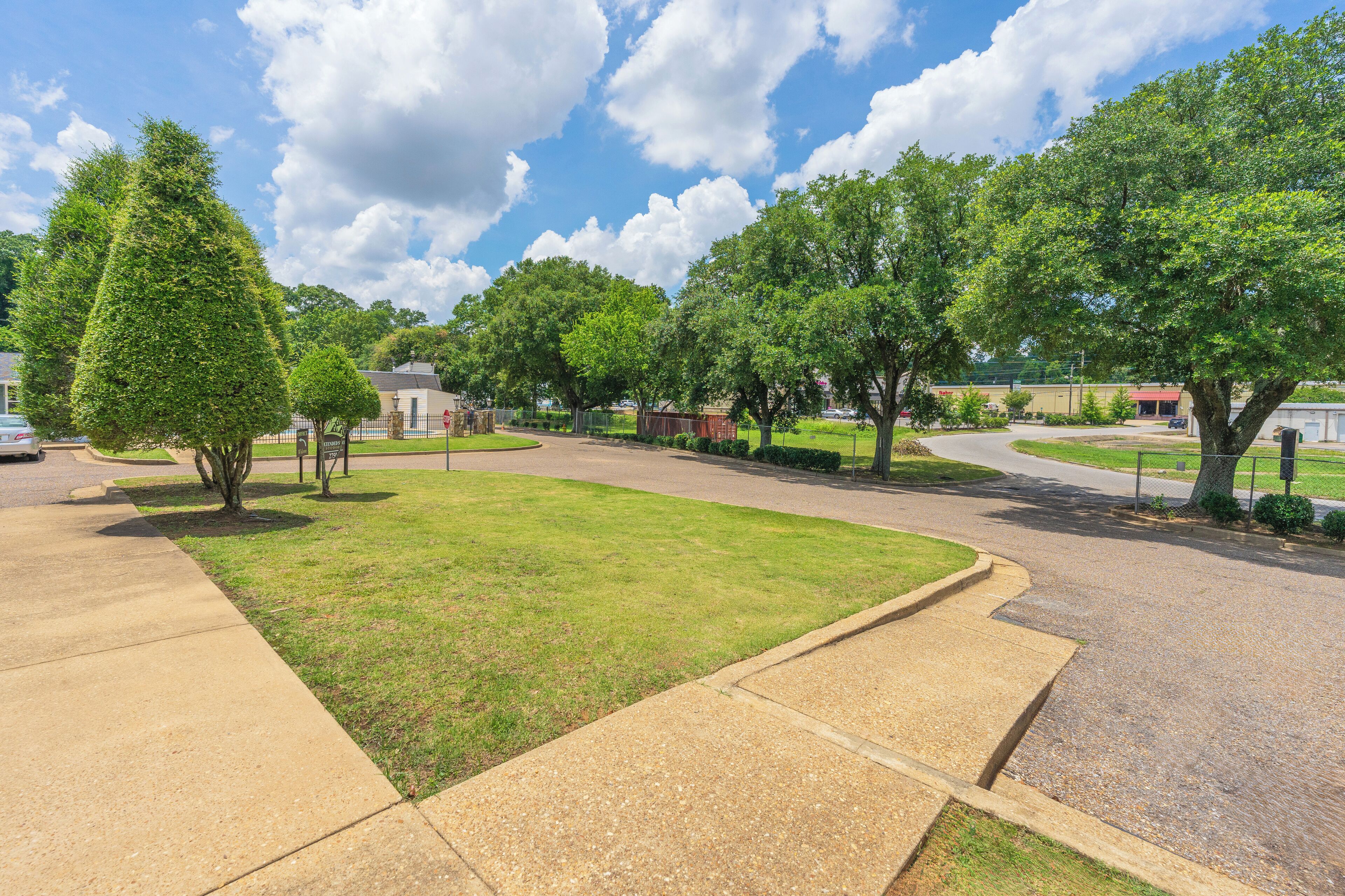 A residential street with houses, trees, and a clear sky.
