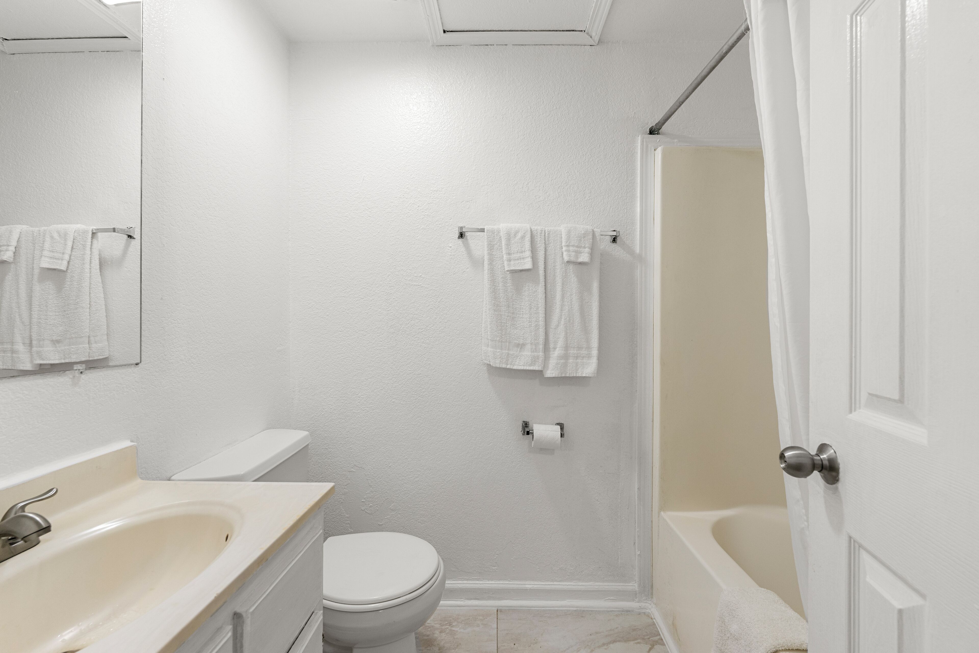 A small, clean bathroom with a toilet, sink, and bathtub.