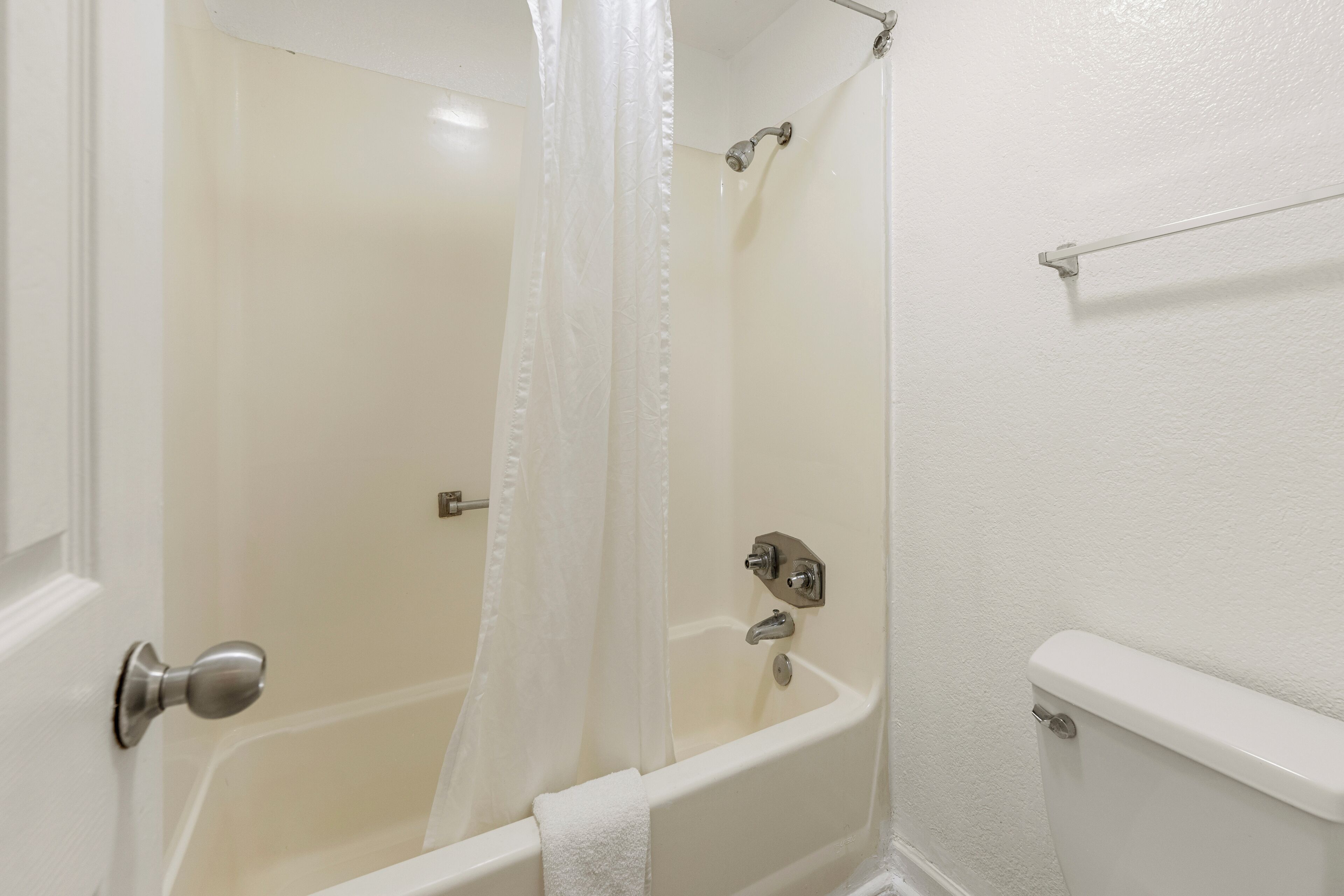A bathroom with a bathtub, a shower curtain, and a toilet.