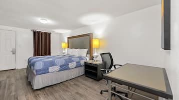 A hotel room with a bed, desk, chair, and two bedside lamps.