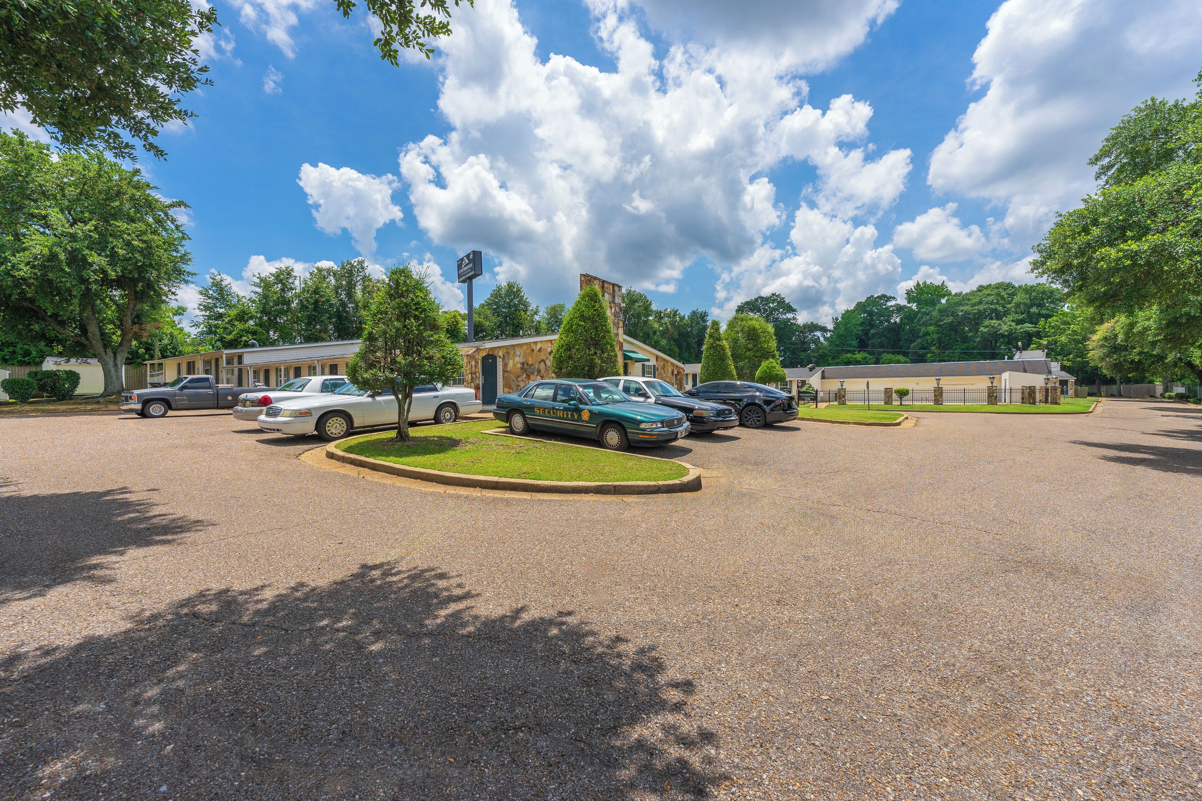 A parking lot with several cars, a building with a stone facade, and trees.