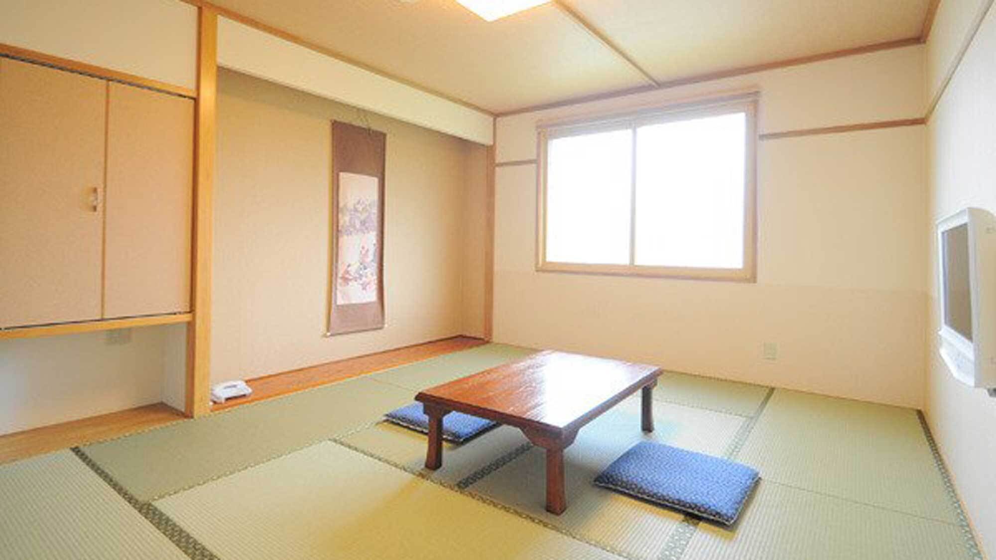 A traditional Japanese room with tatami flooring, a low wooden table, a sliding door, and a large window.