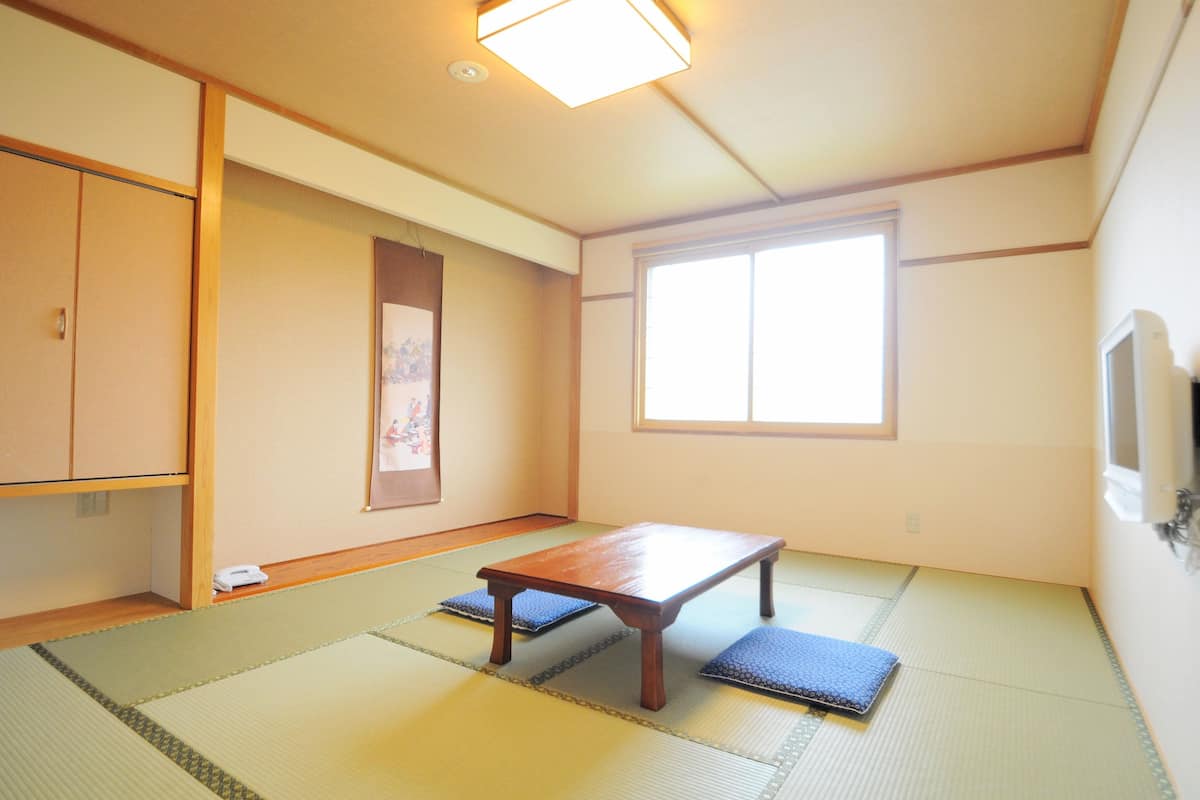 Una habitación japonesa tradicional con suelo de tatami, una mesa de madera baja y puertas correderas.
