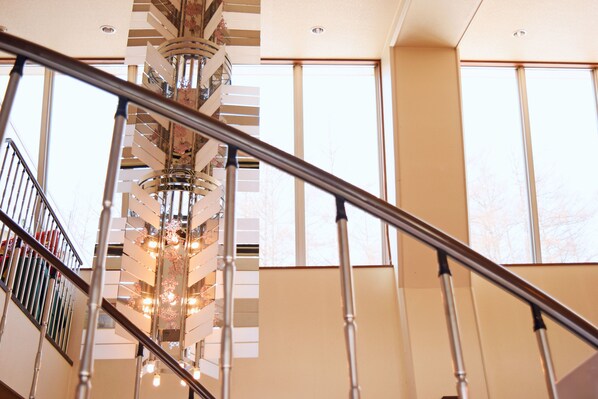 A spiral staircase with a metal railing and a chandelier. - Highland Furano (Furano)
