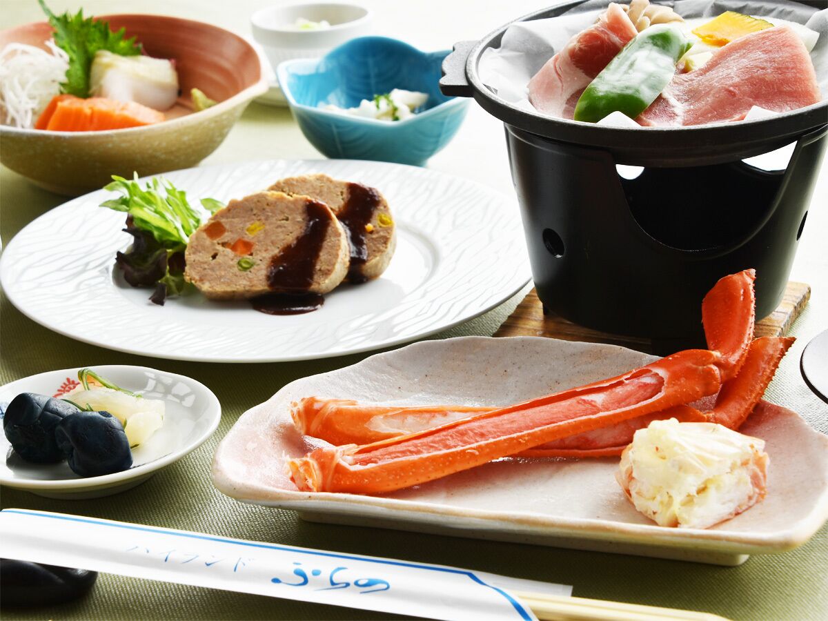 A table with various dishes including seafood, a pot of boiling water, and plates with food.