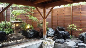 A traditional Japanese garden with a stone lantern, bamboo fence, and rock formations. - Kusatsu Onsen Boun (Kusatsu)