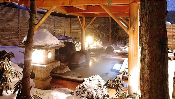 A traditional Japanese hot spring bath area with stone lanterns and wooden structures. - Kusatsu Onsen Boun (Kusatsu)