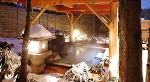 A traditional Japanese hot spring bath area with stone lanterns and wooden structures. - Kusatsu Onsen Boun (Kusatsu)