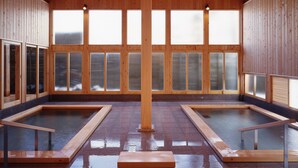 A wooden spa with two hot tubs, large windows, and a high ceiling. - Kusatsu Onsen Boun (Kusatsu)
