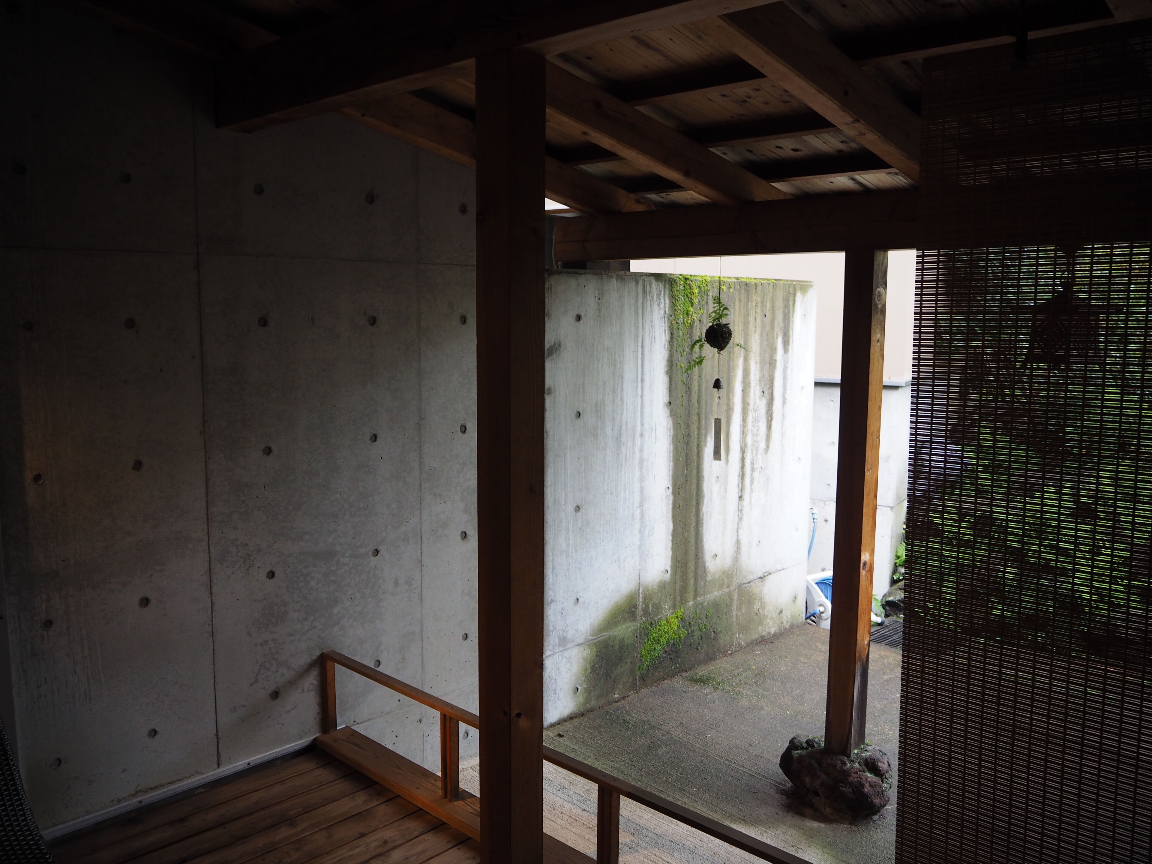 A room with a concrete wall, a wooden floor, and a small window.