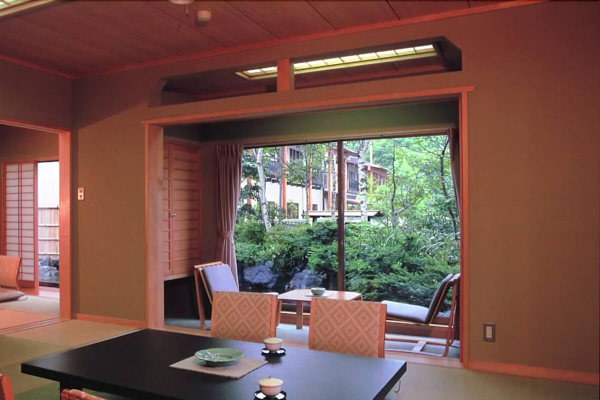 Habitació japonesa tradicional amb sòls de tatami, portes corredisses i vista a un jardí exuberant.