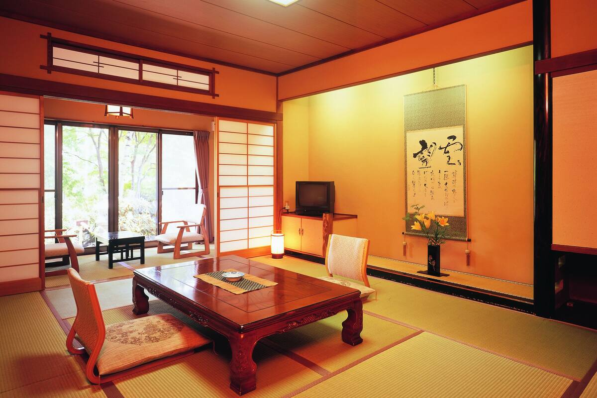Habitació japonesa tradicional amb tatami, una taula de fusta baixa i una televisió.