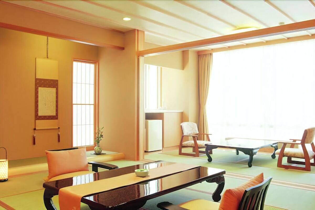 Habitació de planta tradicional japonesa amb fons de tatami, una taula baixa i dues cadires.